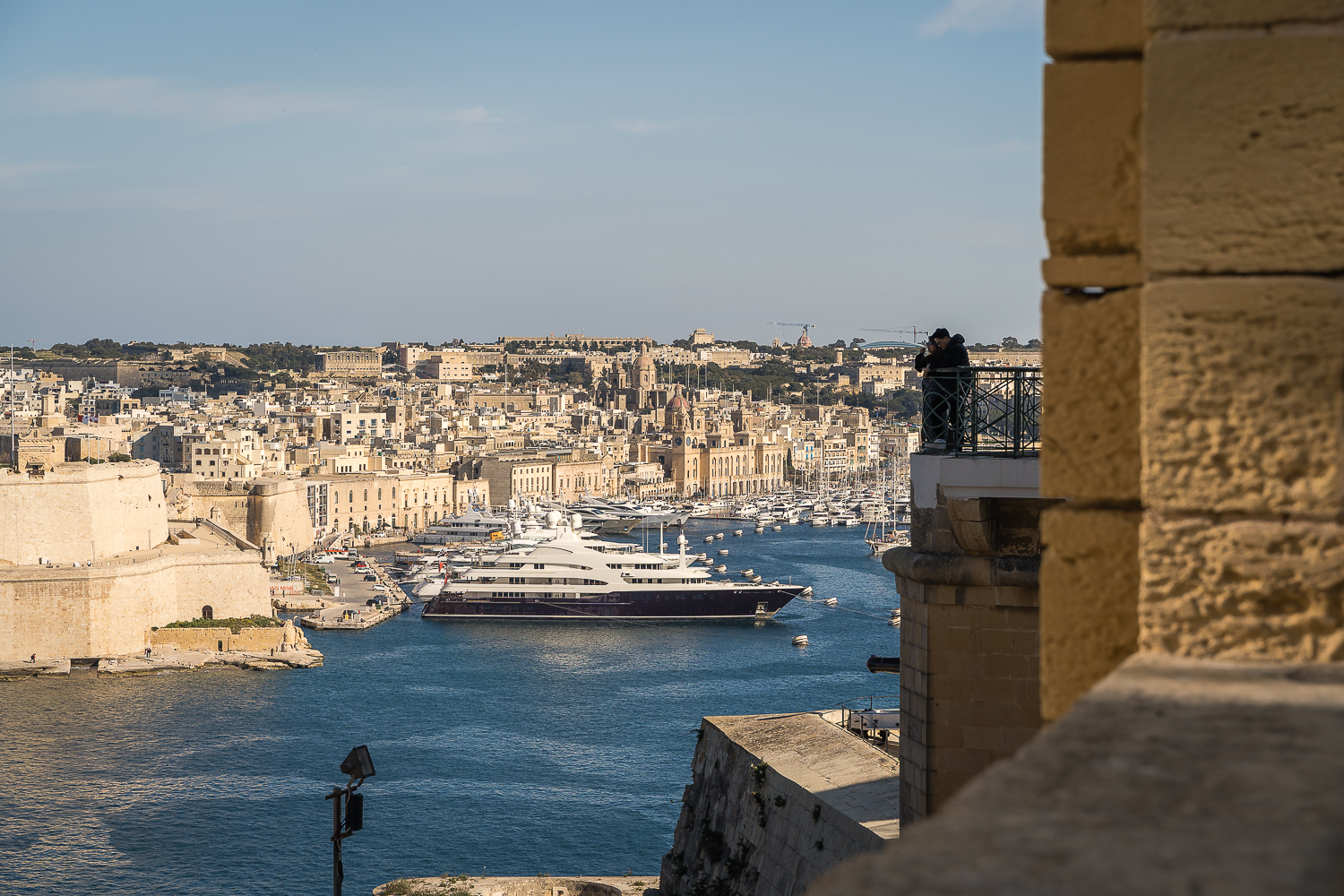 Panoramc view of the Three Cities and the Grand Harbour from the Upper Barrakka Gardens. A couple is enjoying the view from the Upper Barrakka terrace.