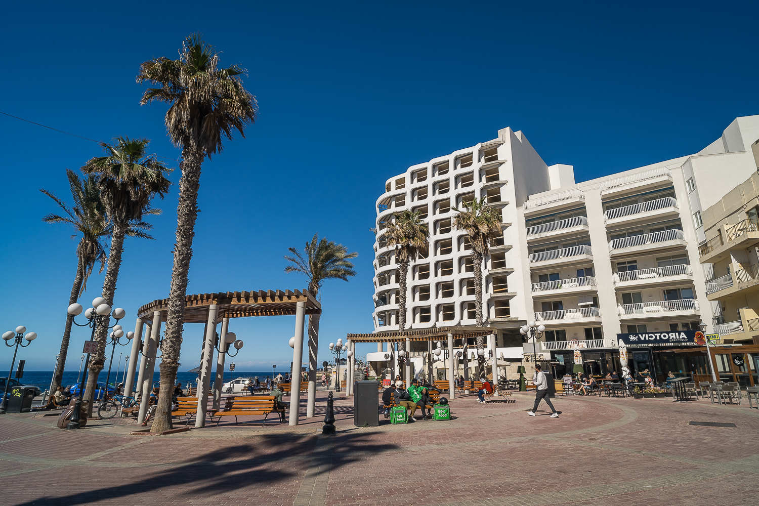 Modern hotels on a square with palm trees in St. Paul's Bay.