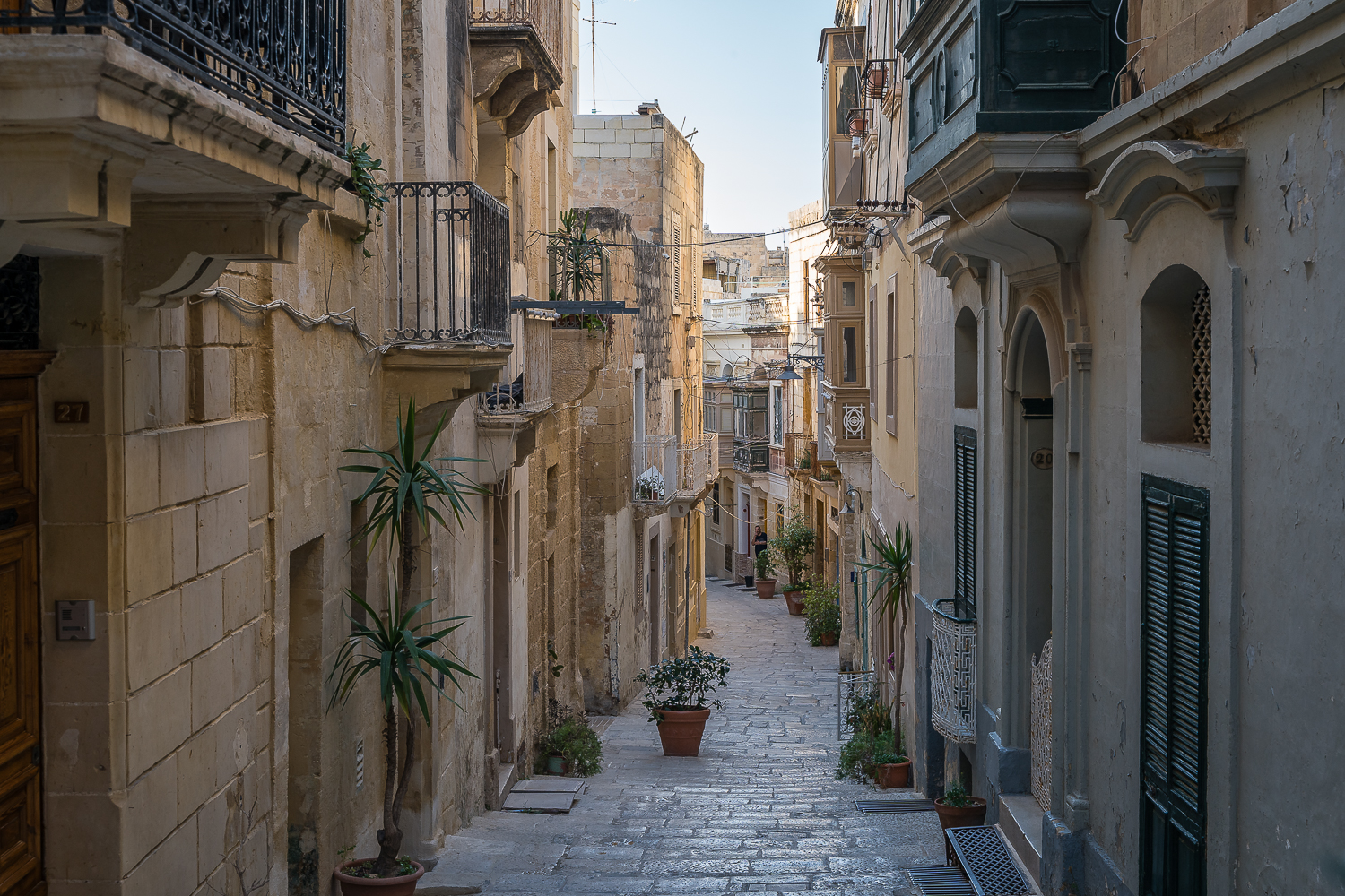 A quaint alley with old buildings adorned with plants in Vittoriosa one of the best options if you're wondering where to stay in Malta without a car.