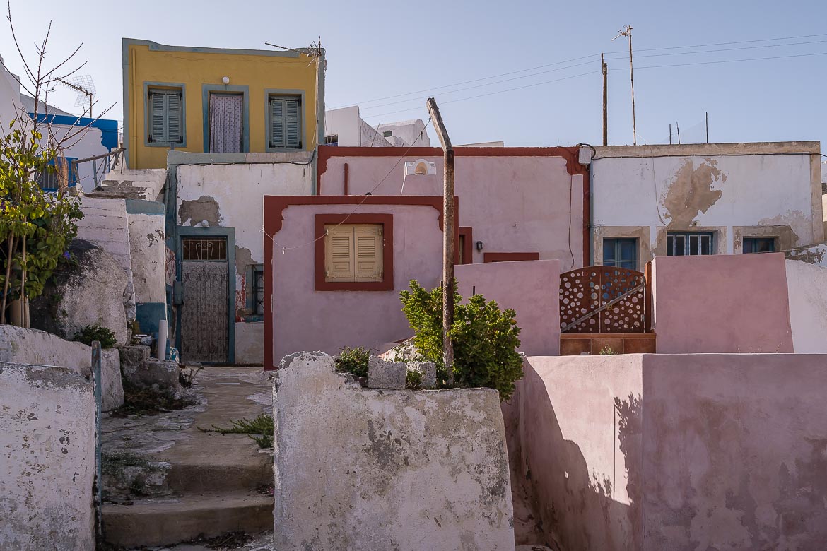 This image shows a yellow, a pink and a white house in Thirassia. They're old and quite neglected but really charming.