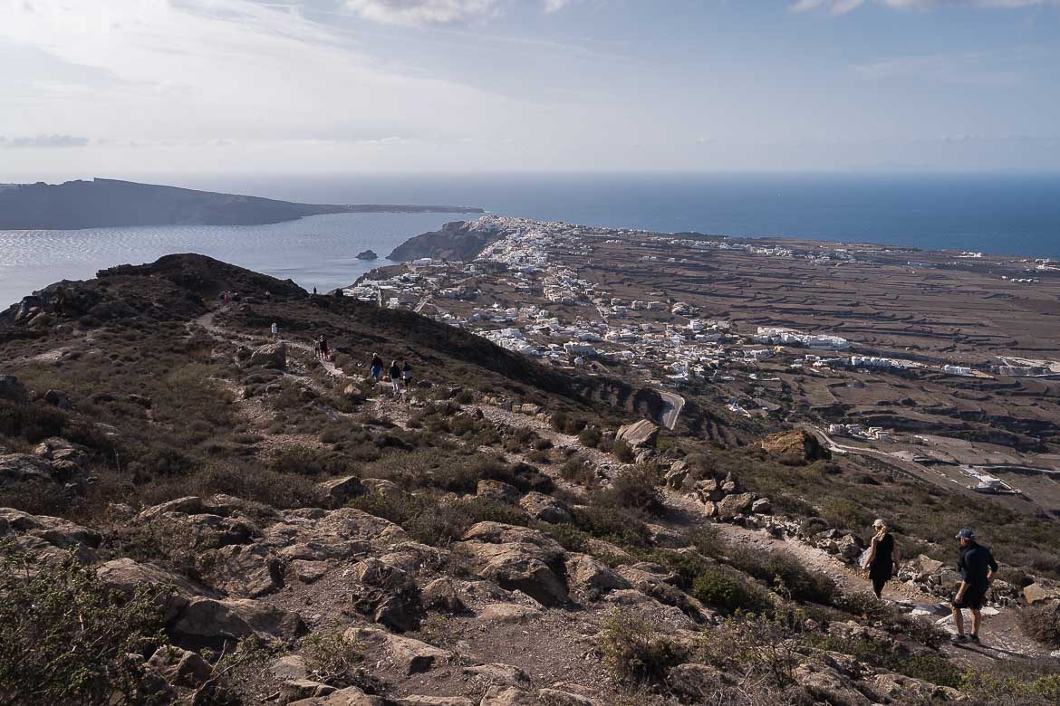 This image shows the final part of the hiking path that leads from Fira to Oia. There are some hikers along the path. In the distance, Oia awaits to welcome them.